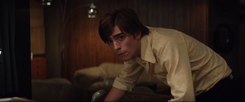 Movie still from “Rocketman” (2019), directed by Dexter Fletcher – A young man is leaning on a couch; Medium shot, High angle