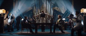 Movie still from “Rocketman” (2019), directed by Dexter Fletcher – A group of people sitting around a table; Wide shot, Low angle
