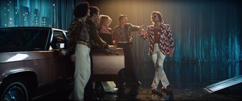 Movie still from “Rocketman” (2019), directed by Dexter Fletcher – A group of people standing in a room; Wide shot, Low angle