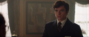 Movie still from “Rocketman” (2019), directed by Dexter Fletcher – A man wearing a suit and tie in front of a painting; Close Up shot, Low angle