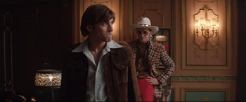 Movie still from “Rocketman” (2019), directed by Dexter Fletcher – A man in a cowboy hat standing next to another man; Medium shot, Low angle