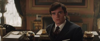 Movie still from “Rocketman” (2019), directed by Dexter Fletcher – A man wearing a suit and tie in a room; Close Up shot, Over the shoulder angle