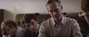 Movie still from “Rocketman” (2019), directed by Dexter Fletcher – An older man and a young boy sitting next to each other on a couch; Close Up shot, Over the shoulder angle