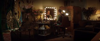 Movie still from “Rocketman” (2019), directed by Dexter Fletcher – A woman sitting in front of a mirror in a room; Wide shot, Over the shoulder angle