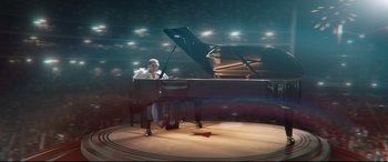 Movie still from “Rocketman” (2019), directed by Dexter Fletcher – A man sitting in front of a grand piano on a stage; Extreme Wide shot, High angle