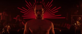 Movie still from “Rocketman” (2019), directed by Dexter Fletcher – A man with no shirt standing in front of a red background; Close Up shot, Low angle