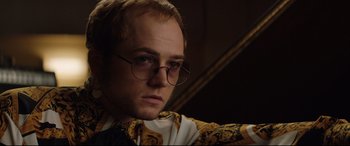 Movie still from “Rocketman” (2019), directed by Dexter Fletcher – A person wearing round glasses; Close Up shot, Low angle