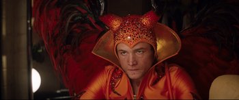 Movie still from “Rocketman” (2019), directed by Dexter Fletcher – A man in a costume with a red and orange hat; Close Up shot, Low angle
