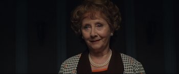 Movie still from “Rocketman” (2019), directed by Dexter Fletcher – An older woman wearing pearls and a jacket; Close Up shot, Over the shoulder angle