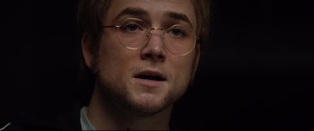 Movie still from “Rocketman” (2019), directed by Dexter Fletcher – A person wearing round glasses; Close Up shot, Over the shoulder angle