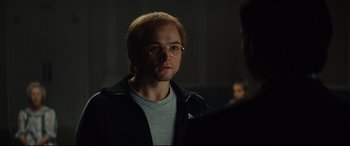 Movie still from “Rocketman” (2019), directed by Dexter Fletcher – A man in a black jacket is looking at the camera; Close Up shot, Over the shoulder angle