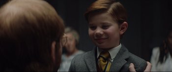 Movie still from “Rocketman” (2019), directed by Dexter Fletcher – A young boy in a suit and tie smiling; Close Up shot, Over the shoulder angle