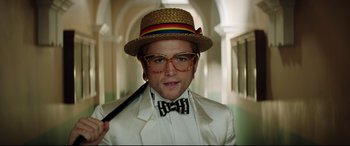Movie still from “Rocketman” (2019), directed by Dexter Fletcher – A man wearing a straw hat and a bow tie; Close Up shot, Low angle