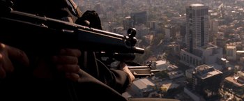Movie still from “Romeo + Juliet” (1996), directed by Baz Luhrmann – A man holding a gun while looking out a window; Medium shot, High angle