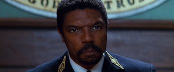 Movie still from “Romeo + Juliet” (1996), directed by Baz Luhrmann – A person wearing a suit and tie; Close Up shot, Low angle