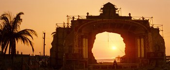 Movie still from “Romeo + Juliet” (1996), directed by Baz Luhrmann – The sun is setting over the ocean with a building in the background; Extreme Wide shot, Low angle