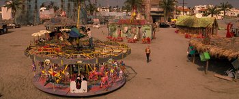 Movie still from “Romeo + Juliet” (1996), directed by Baz Luhrmann – A man walking down a street next to an amusement park ride; Extreme Wide shot, High angle