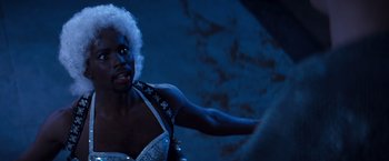 Movie still from “Romeo + Juliet” (1996), directed by Baz Luhrmann – A woman in a white and black dress is holding a white object; Close Up shot, Over the shoulder angle