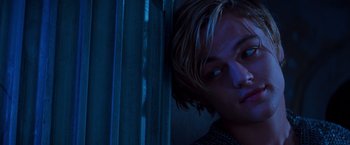 Movie still from “Romeo + Juliet” (1996), directed by Baz Luhrmann – A young man with blonde hair leaning up against a wall; Close Up shot, Overhead angle
