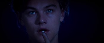 Movie still from “Romeo + Juliet” (1996), directed by Baz Luhrmann – A young man with blue eyes is holding his finger to his mouth; Extreme Close Up shot, Low angle