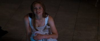 Movie still from “Romeo + Juliet” (1996), directed by Baz Luhrmann – A young woman in a white dress smiling for the camera; Medium shot, High angle