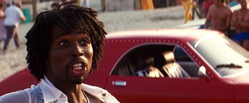 Movie still from “Romeo + Juliet” (1996), directed by Baz Luhrmann – A man with dreads standing in front of a red car; Close Up shot, Low angle
