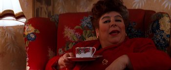 Movie still from “Romeo + Juliet” (1996), directed by Baz Luhrmann – A woman holding a cup of tea on a couch; Close Up shot, High angle