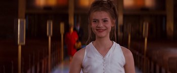Movie still from “Romeo + Juliet” (1996), directed by Baz Luhrmann – A girl in a white dress smiling for the camera; Close Up shot, Over the shoulder angle
