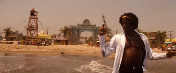 Movie still from “Romeo + Juliet” (1996), directed by Baz Luhrmann – A man standing on a beach holding a knife; Medium shot, Low angle