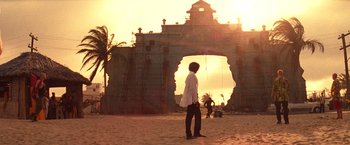 Movie still from “Romeo + Juliet” (1996), directed by Baz Luhrmann – A man standing on the beach in front of an archway at sunset; Extreme Wide shot, Low angle