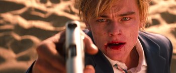 Movie still from “Romeo + Juliet” (1996), directed by Baz Luhrmann – A man with a gun in his hand and blood on his face; Close Up shot, Low angle