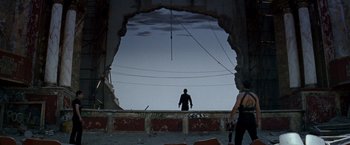 Movie still from “Romeo + Juliet” (1996), directed by Baz Luhrmann – A man standing on a ledge looking out a hole in the wall; Extreme Wide shot, Low angle