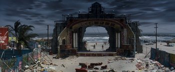 Movie still from “Romeo + Juliet” (1996), directed by Baz Luhrmann – A beach with people standing on the sand and a building on the beach; Extreme Wide shot, High angle