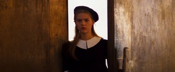 Movie still from “Romeo + Juliet” (1996), directed by Baz Luhrmann – A young woman wearing a hat standing in front of a door; Close Up shot, Low angle
