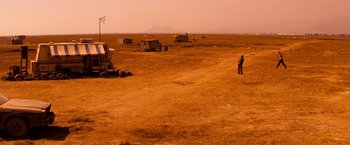 Movie still from “Romeo + Juliet” (1996), directed by Baz Luhrmann – A man standing in a field with a kite in the background; Extreme Wide shot, High angle