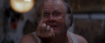 Movie still from “Romeo + Juliet” (1996), directed by Baz Luhrmann – An older man holding a yellow pencil in his hand; Extreme Close Up shot, Low angle