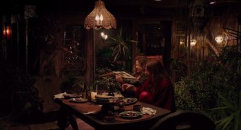 Movie still from “Ruby Sparks” (2012), directed by Valerie Faris – Two women sitting at a dinner table reading a magazine; Wide shot, High angle