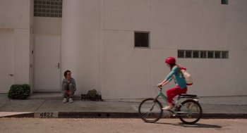 Movie still from “Ruby Sparks” (2012), directed by Valerie Faris – A woman sitting on the ground next to a bicycle; Wide shot, Over the shoulder angle
