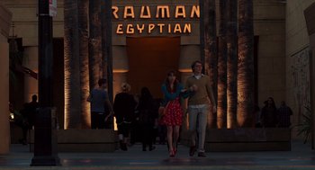 Movie still from “Ruby Sparks” (2012), directed by Valerie Faris – A couple of people that are standing in front of a building; Wide shot, Over the shoulder angle