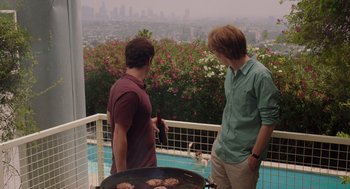 Movie still from “Ruby Sparks” (2012), directed by Valerie Faris – Two young men standing next to each other near an outdoor grill; Medium shot, Over the shoulder angle