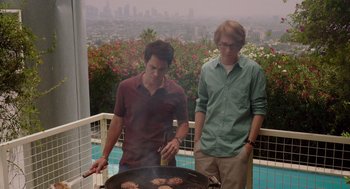 Movie still from “Ruby Sparks” (2012), directed by Valerie Faris – Two young men are cooking hamburgers on a grill; Medium shot, Over the shoulder angle