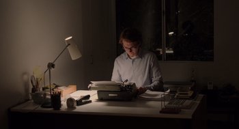 Movie still from “Ruby Sparks” (2012), directed by Valerie Faris – A man sitting at a desk writing on a typewriter; Medium shot, High angle