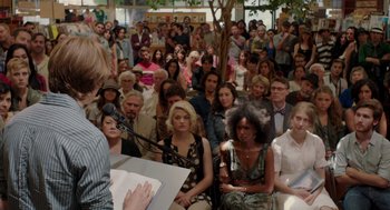 Movie still from “Ruby Sparks” (2012), directed by Valerie Faris – A group of people sitting in a room with a microphone; Medium shot, Over the shoulder angle