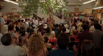 Movie still from “Ruby Sparks” (2012), directed by Valerie Faris – A crowd of people sitting in a room with a tree; Wide shot, High angle