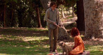 Movie still from “Ruby Sparks” (2012), directed by Valerie Faris – A man and a woman playing with a dog in a park; Wide shot, Over the shoulder angle