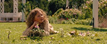 Movie still from “Saving Mr. Banks” (2013), directed by John Lee Hancock – A girl laying in the grass with a flower in her hand; Medium shot, High angle