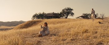 Movie still from “Saving Mr. Banks” (2013), directed by John Lee Hancock – A woman sitting on the ground in the middle of a dry grass field; Wide shot, Low angle