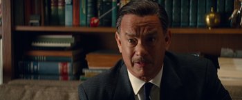 Movie still from “Saving Mr. Banks” (2013), directed by John Lee Hancock – A man in a suit and tie in front of a bookshelf; Close Up shot, Over the shoulder angle