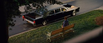 Movie still from “Saving Mr. Banks” (2013), directed by John Lee Hancock – A man sitting on a bench in front of a black car; Wide shot, High angle
