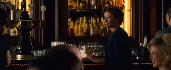 Movie still from “Saving Mr. Banks” (2013), directed by John Lee Hancock – A woman sitting at a bar in front of a bunch of liquor bottles; Medium shot, Over the shoulder angle